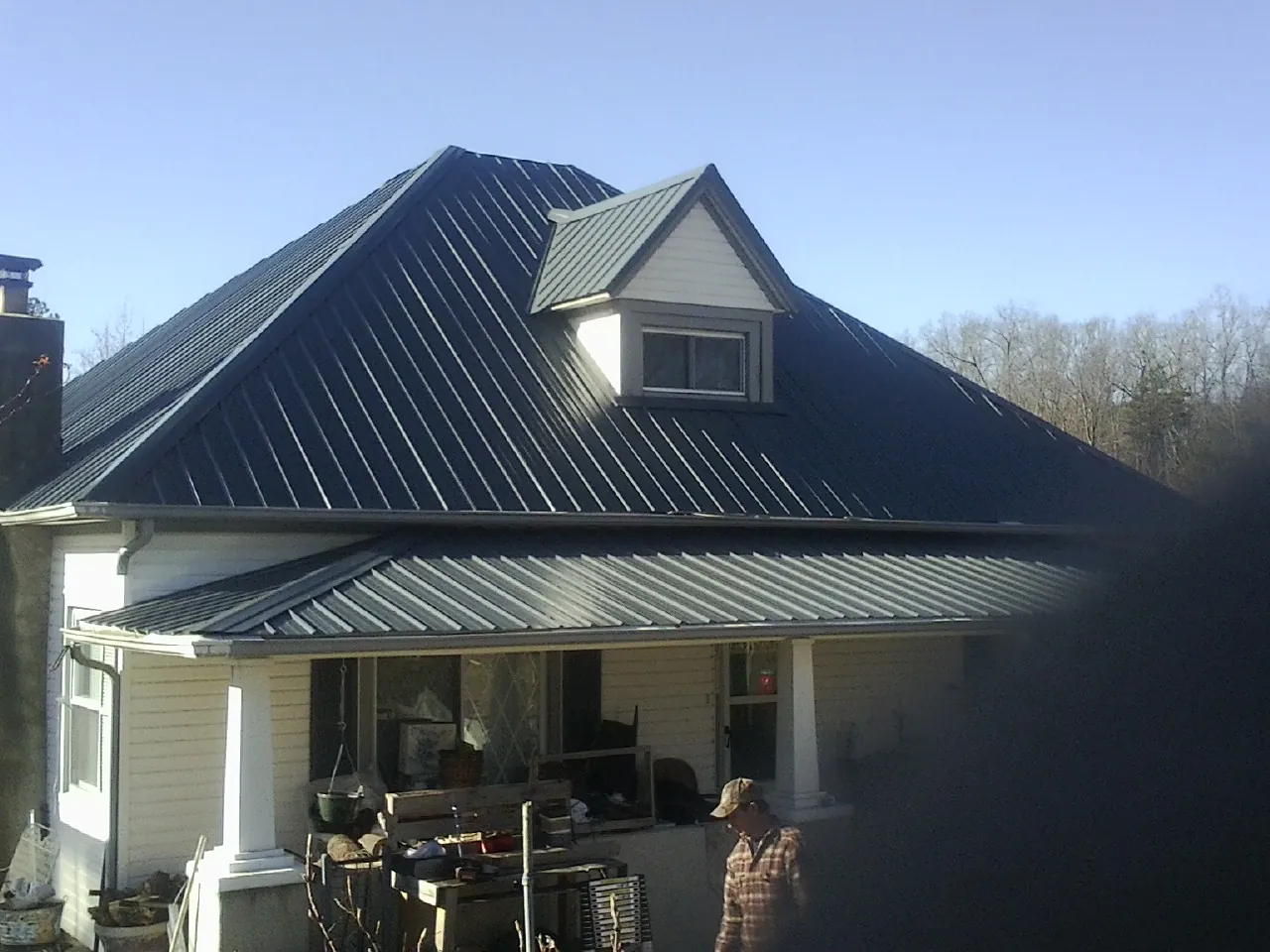 Dark blue standing seam metal roof with a dormer above a front porch in Centerville